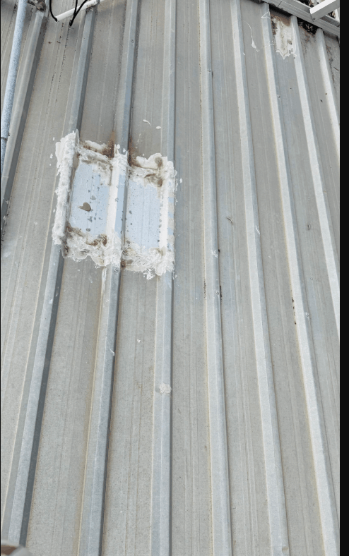 Previous repair patch and sealant on commercial metal roof sheeting