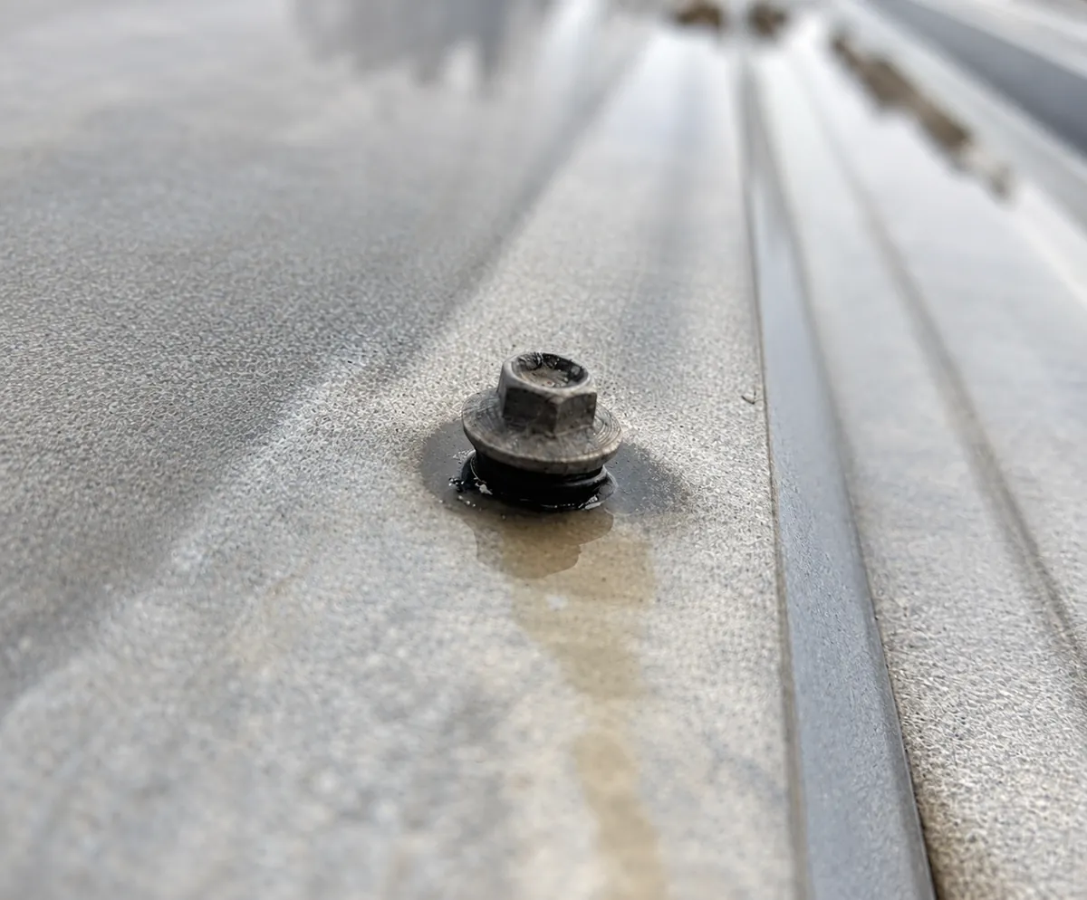 Water staining around a failed roof screw fastener causing a leak