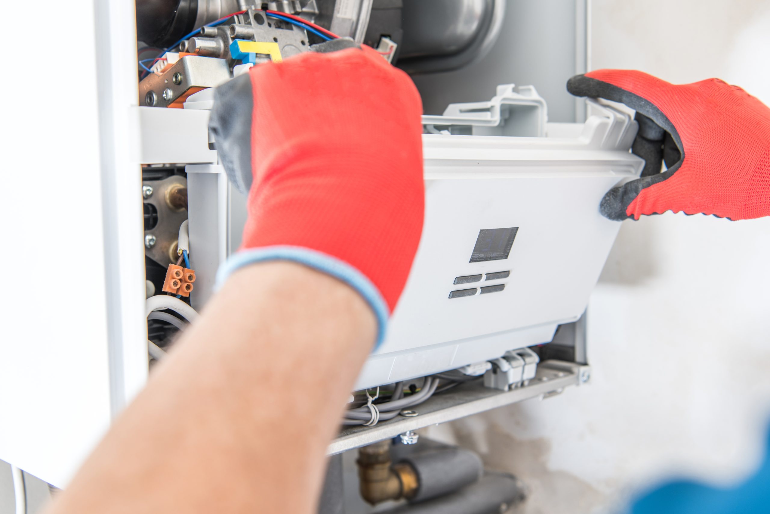 Technician inspecting a commercial hot water system and associated pipework.