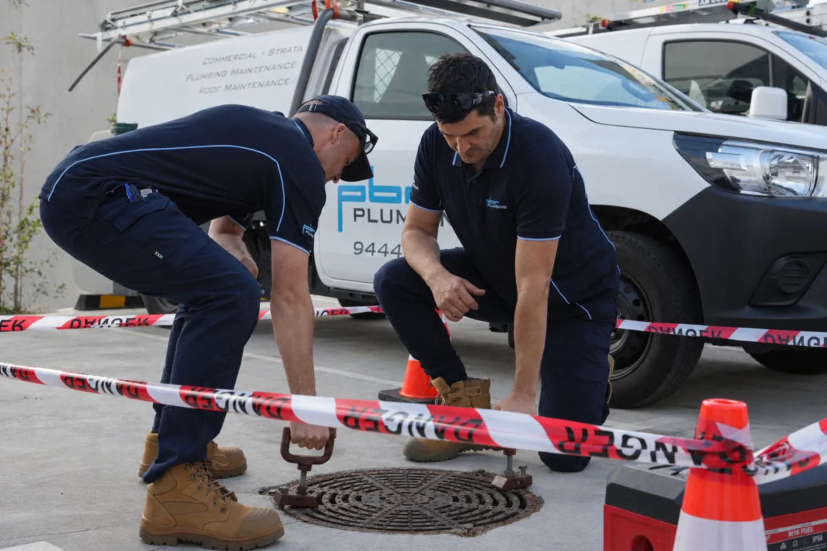 Plumbers inspecting a stormwater pit as part of drain maintenance